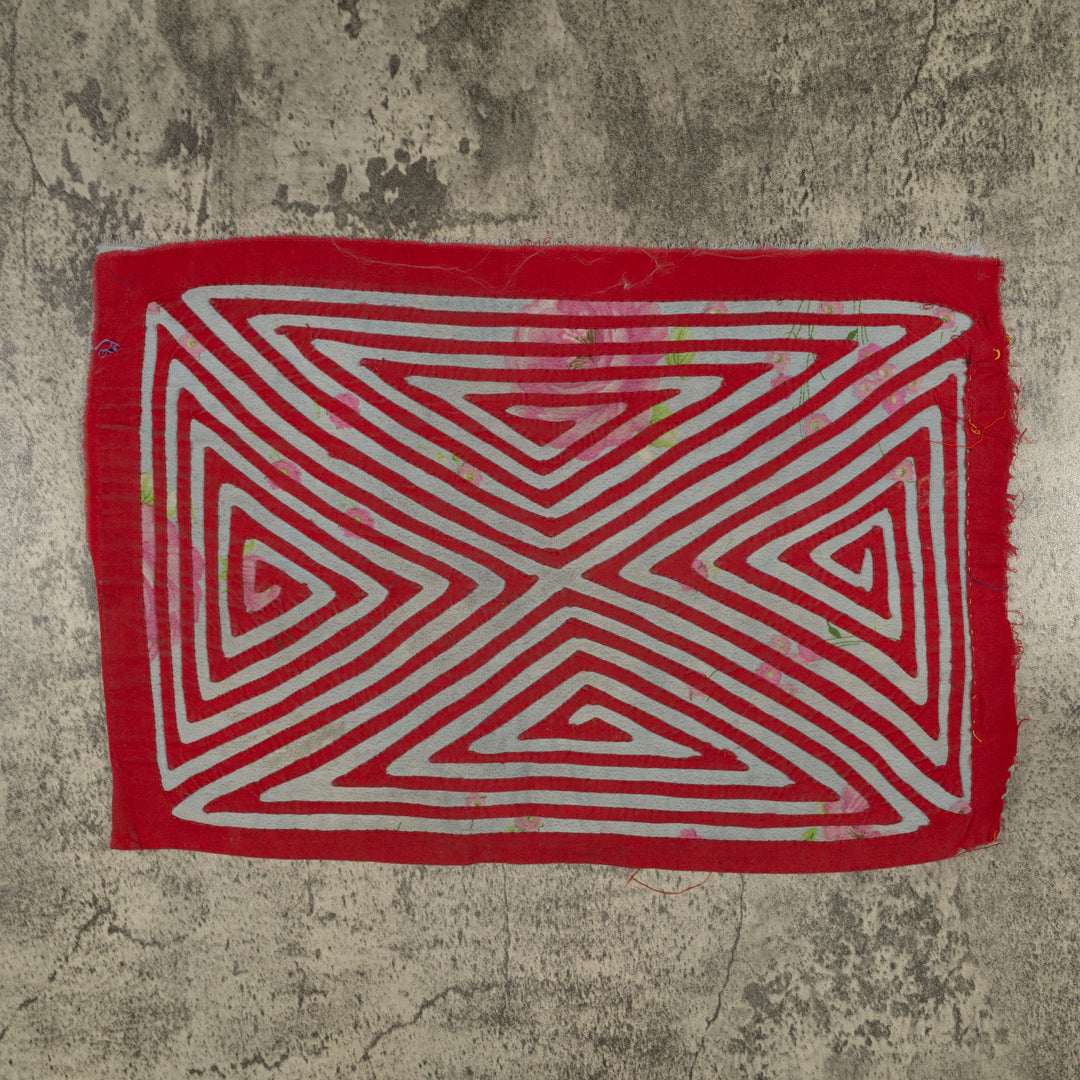 Panama mola panel, nested triangles meeting in an X over rose print cloth, hand stitched reverse applique