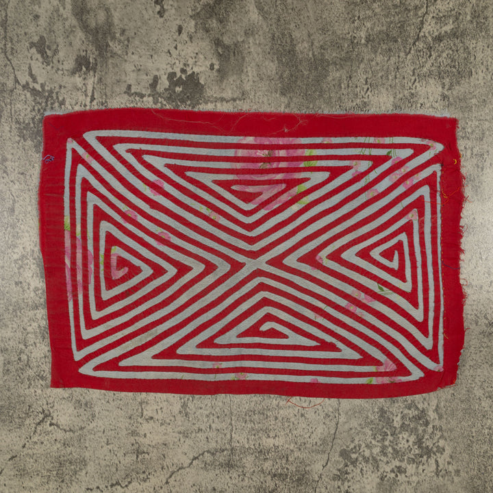 Panama mola panel, nested triangles meeting in an X over rose print cloth, hand stitched reverse applique
