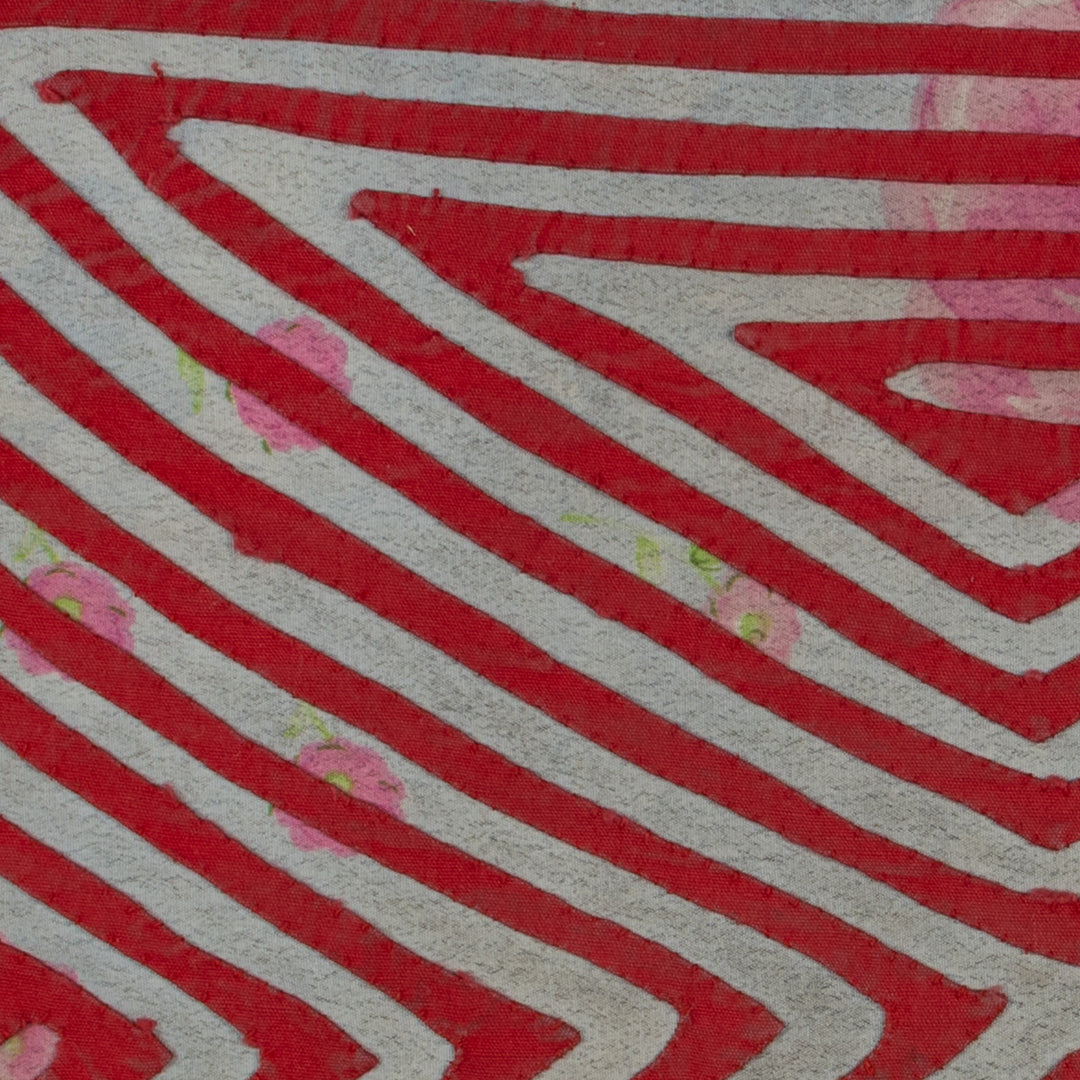 Panama mola panel, nested triangles meeting in an X over rose print cloth, hand stitched reverse applique