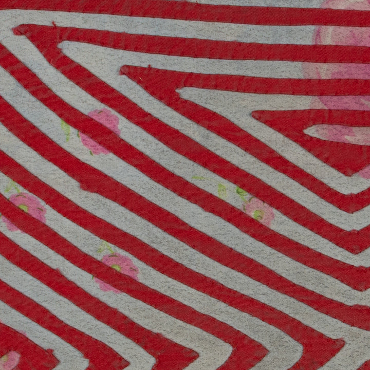 Panama mola panel, nested triangles meeting in an X over rose print cloth, hand stitched reverse applique