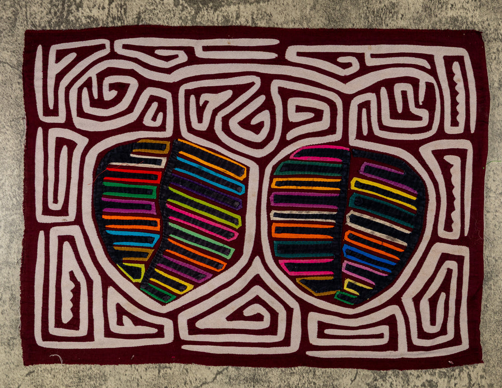 Panama mola panel, two striped fruit shapes in a white maze on maroon, hand stitched reverse applique