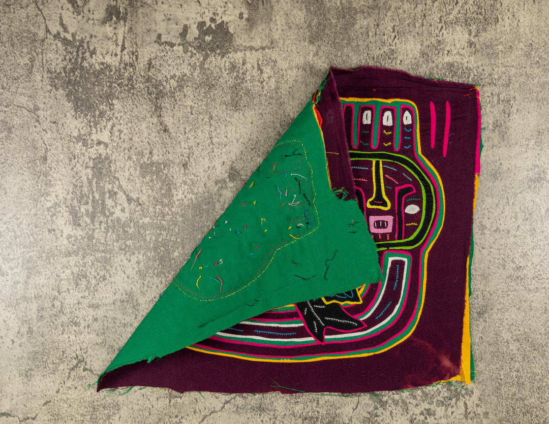 Hand stitched Guna mola from Guna Yala Panama, the parrot tucked beside the faces