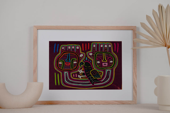 Panama mola panel, two big square faces and a dark parrot on maroon, hand stitched reverse applique