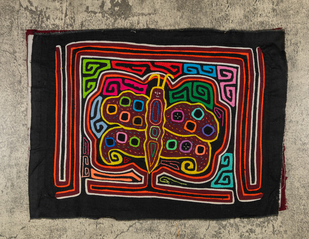 Panama mola panel, butterfly with polka dot wings and a smiling face on black, hand stitched reverse applique