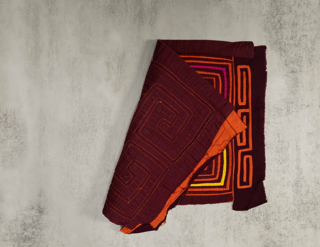 Hand stitched Guna mola from Guna Yala Panama, square spirals in orange on maroon