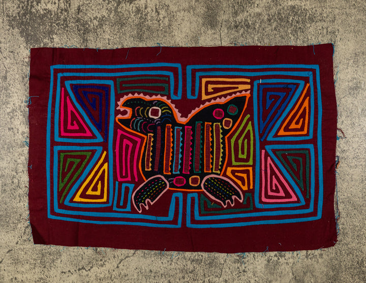 Panama mola panel, crested creature with a striped body and clawed feet in turquoise outline, hand stitched reverse applique