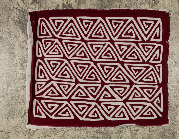 Panama mola panel, rows of white triangular spirals turning inward on maroon, hand stitched reverse applique