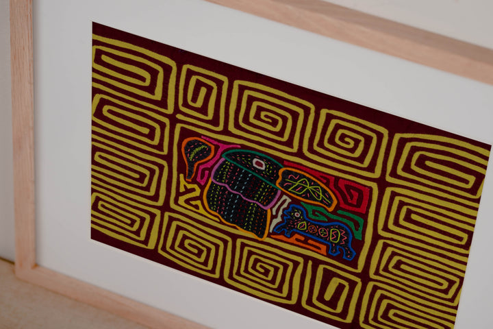 Hand stitched Guna mola from Guna Yala Panama, yellow spiral border running around the maroon center
