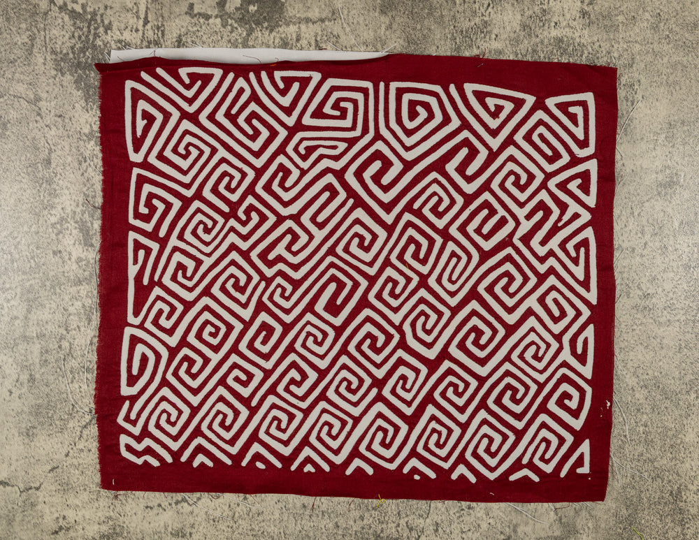 Panama mola panel, white key pattern running diagonally across maroon cloth, hand stitched reverse applique