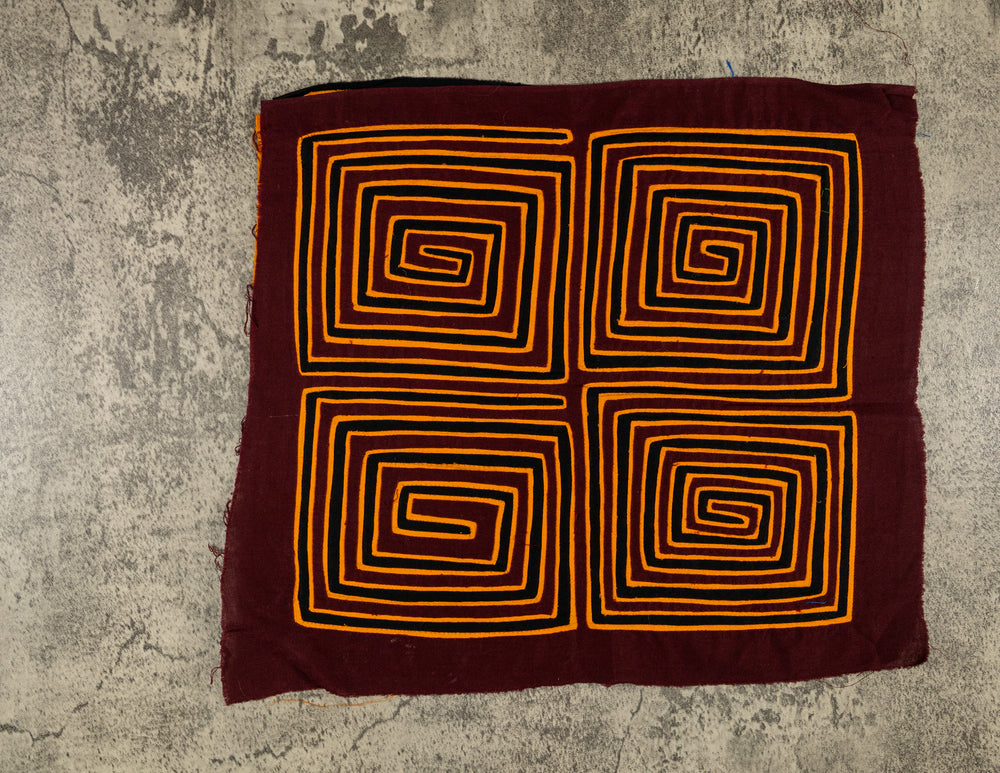Panama mola panel, four orange square spirals winding inward on maroon, hand stitched reverse applique