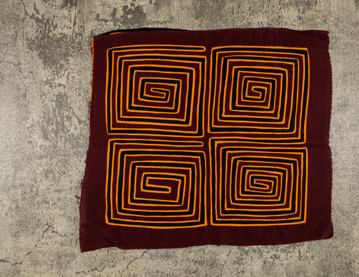 Panama mola panel, four orange square spirals winding inward on maroon, hand stitched reverse applique