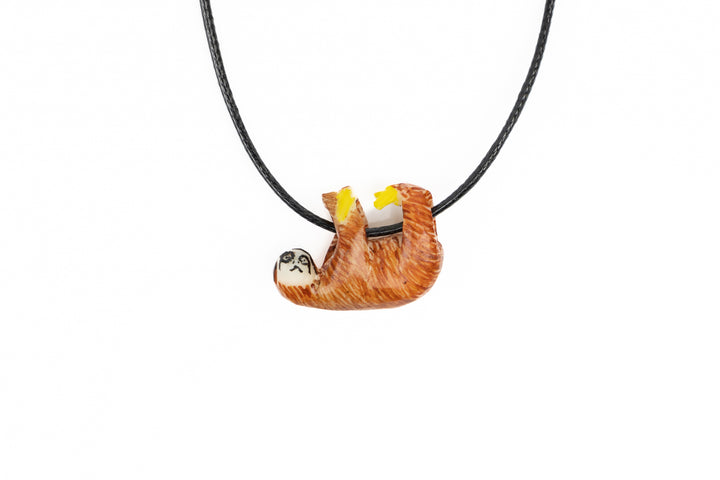 Tagua sloth necklace, rust-orange carved with yellow accents, black cord