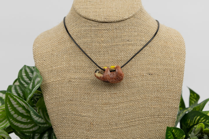 Sloth tagua necklace on packaging with wood elements